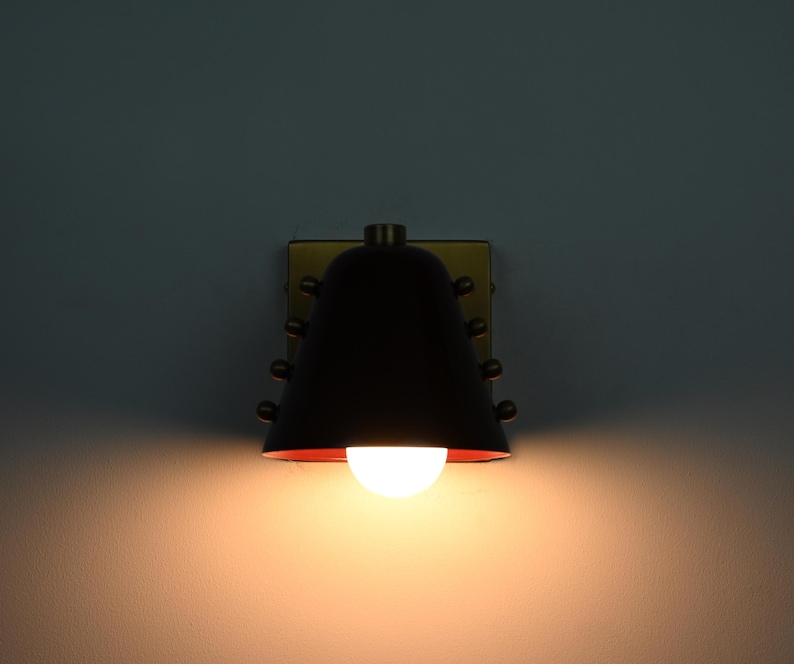 This Compact Cone Wall Sconce Combines a Wine Colored Shade with Handcrafted Brass Components, Creating a Bold Contrast Between the Rich Shade and Warm Metal While Maintaining a Simple Architectural Form, Frost Lights.