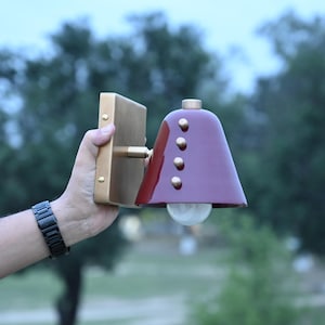 Angled Product View of A Handcrafted Wall Sconce with A Deep Wine Cone Shade and Brass Construction, Revealing the Shade Projection, Decorative Rivet Details, and Clean Proportions of The Compact Fixture, Frost Lights.