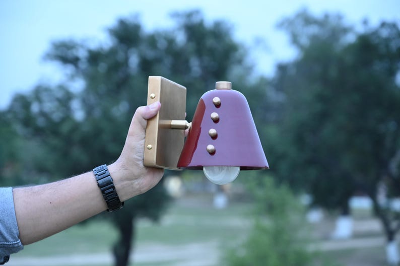 Angled Product View of A Handcrafted Wall Sconce with A Deep Wine Cone Shade and Brass Construction, Revealing the Shade Projection, Decorative Rivet Details, and Clean Proportions of The Compact Fixture, Frost Lights.
