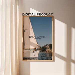 May include: A rectangular wall art print in a light wood frame featuring a sailboat on blue water with mountains in the background. The text RALPH LAUREN SUMMER 1944 is centered on the image. The words DIGITAL PRODUCT appear above the frame.