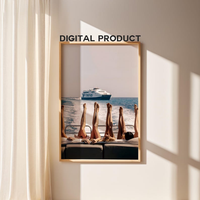 May include: A framed print featuring a boat on the ocean with several pairs of legs in the air. The text "DIGITAL PRODUCT" is printed at the top of the frame. The image is displayed on a white wall with a beige curtain.