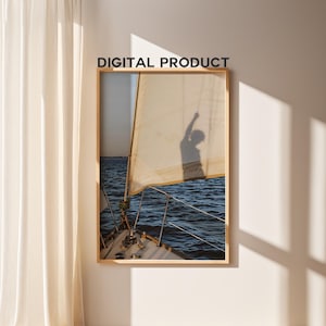 May include: A framed print of a sailboat at sea, with a beige sail and a shadow of a person with their arm raised. The image is set against a backdrop of blue water and a clear sky. The text "DIGITAL PRODUCT" is at the top.
