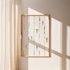 May include: A framed art print featuring a minimalist design of swimmers in a pool. The artwork showcases figures in various swimsuits, positioned along vertical blue lines against a white background. The frame is made of light-colored wood.
