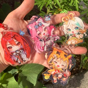 Op de afbeelding: Vier anime-personage sleutelhangers met kleurrijke ontwerpen. De sleutelhangers zijn gemaakt van helder acryl en tonen personages met verschillende kapsels, outfits en accessoires.