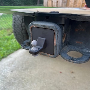 Könnte beinhalten: Eine schwarze Anhängerkupplung aus Metall mit einer silbernen Kugelkupplung. Die Kupplung ist an einem schwarzen LKW befestigt.