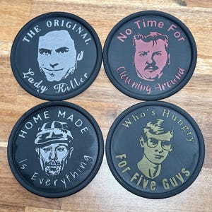 Puede incluir: Cuatro posavasos redondos negros con retratos y texto. Uno dice "The Original Lady Killer", otro "No Time For Clowning Around", un tercero "Home Made Is Everything" y el último "Who's Hungry For Five Guys".