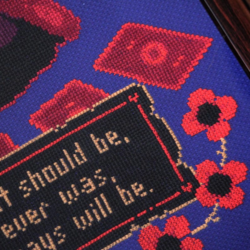 May include: A black and white cross-stitch design with the text "It should be.  Always was.  Always will be."  The design is surrounded by red flowers with black centers.