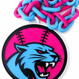 May include: A round, pink and blue pendant featuring a stylized tiger head with a baseball stitch design. The pendant is connected to a chain of interlocking pink and blue links. The design is set against a white background.