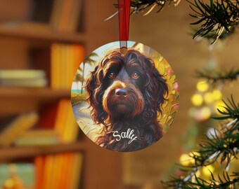 May include: Circular Christmas decoration with a detailed portrait of a brown dog, the name "Sally" in white script. The ornament has a red ribbon for hanging and is set against a blurred background of a tropical scene.