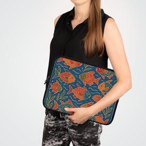 May include: A blue laptop sleeve featuring a repeating pattern of orange, red, and green fish. The fish are stylized with detailed scales and fins, set against a blue background with white wave and green leaf accents. The sleeve has a black zipper.