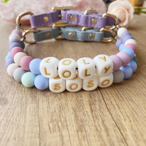 Può includere: Un collare per cani in silicone con perline color pastello con il nome "LOLY SOSO" scritto in perline bianche con lettere dorate.