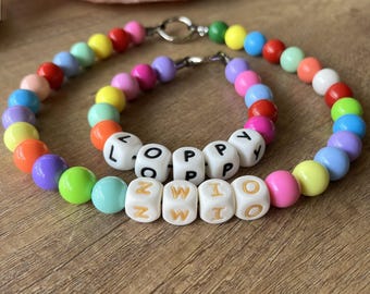 May include: Two colorful beaded bracelets with white letter beads spelling out the names "LOPPY" and "ZWIO".