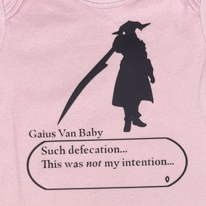 May include: Pink baby onesie with a black silhouette of a character holding a weapon and a speech bubble that says "Gaius Van Baby Such defecation... This was not my intention..."