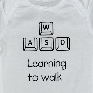 Mono de computadora adorable y nerd para bebés gamers que aprenden a caminar, WASD, vinilo termoadhesivo, personalizable para 3, 6, 9, 12 y 18 meses