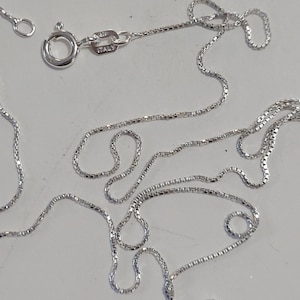 May include: A silver chain necklace with a lobster clasp and a tag that reads "925 ITALY".