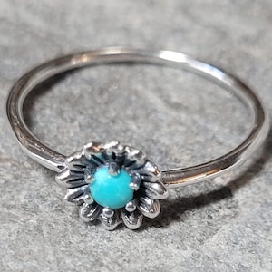 May include: A silver ring with a turquoise gemstone set in a flower design.