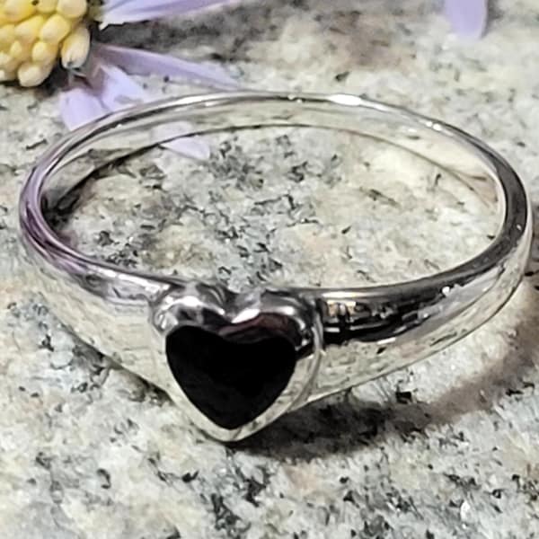 May include: A silver ring with a black heart-shaped stone.