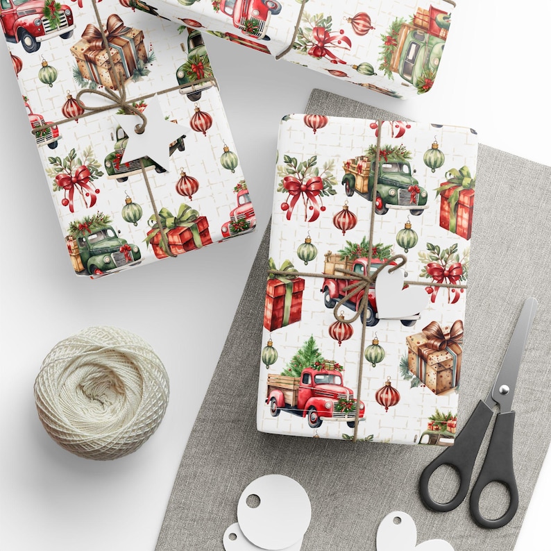 May include: Wrapping paper featuring a repeating pattern of red and green vintage trucks carrying Christmas trees, red gift boxes, and hanging ornaments on a white background. The paper is tied with twine and includes white star-shaped gift tags.