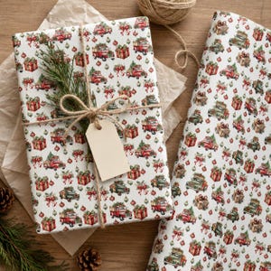 May include: White wrapping paper featuring a repeating pattern of red and green vintage trucks carrying Christmas trees, wrapped gift boxes, and hanging ornaments. The paper is tied with brown twine and includes a blank beige gift tag.