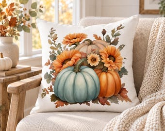 May include: A square throw pillow featuring a printed illustration of a seasonal arrangement. The design displays a light blue pumpkin, an orange pumpkin, and a pale pumpkin surrounded by orange sunflowers and various autumn-colored foliage.