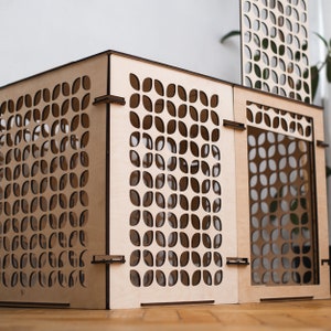 May include: A wooden box with a geometric pattern cut out design. The box is made of light wood and has a square shape.