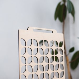 May include: A wooden divider with a geometric pattern of cut-out leaves. The divider has a handle at the top.