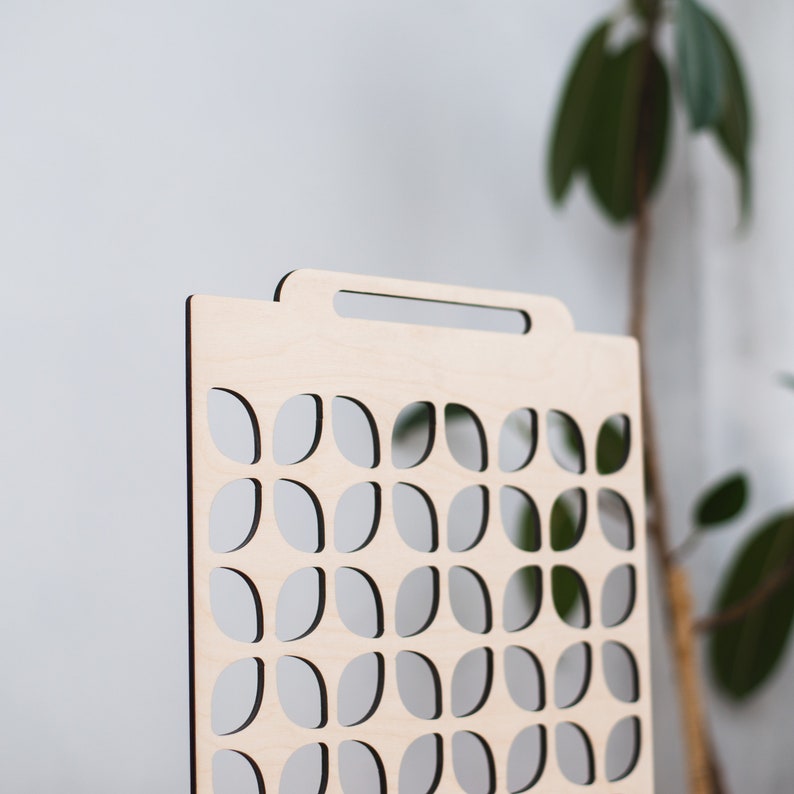 May include: A wooden divider with a geometric pattern of cut-out leaves. The divider has a handle at the top.