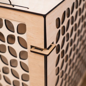 May include: A wooden box with a black trim and a patterned design. The box has a hinged lid and a latch.