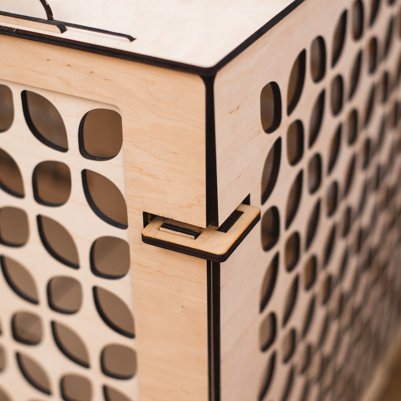 May include: A wooden box with a black trim and a patterned design. The box has a hinged lid and a latch.