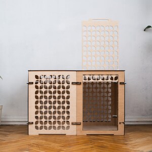 May include: A wooden cat house with a geometric pattern. The house has a removable top panel and a door on the front. The house is made of light wood and has a natural finish.