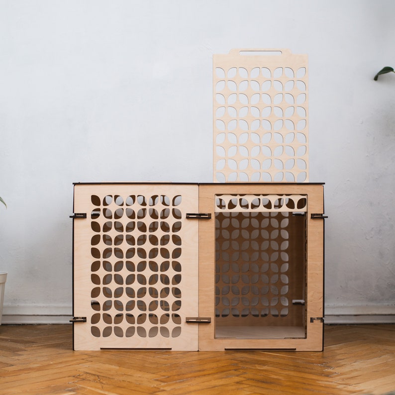 May include: A wooden cat house with a geometric pattern. The house has a removable top panel and a door on the front. The house is made of light wood and has a natural finish.