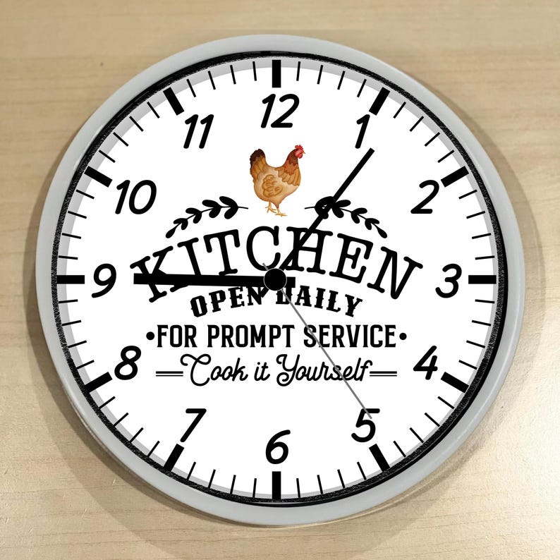 May include: White kitchen clock with black numbers and hands. The clock has a black and white image of a chicken and the text "Kitchen Open Daily - For Prompt Service: Cook it Yourself".