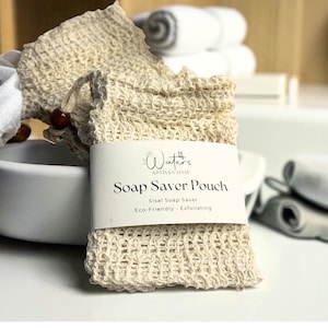 May include: A beige sisal soap saver pouch with a drawstring closure and a wooden bead. The pouch has a label that reads "Waters Artisan Soap Soap Saver Pouch Sisal Soap Saver Eco-Friendly Exfoliating."