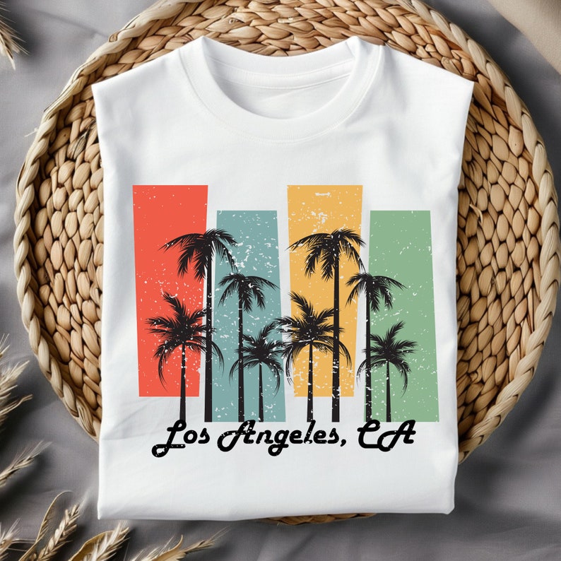 May include: White t-shirt with a vintage-style graphic of palm trees and the text "Los Angeles, CA".