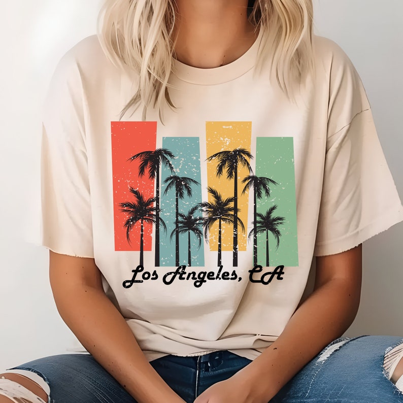 May include: A beige t-shirt with a vintage-style graphic of palm trees and the text "Los Angeles, CA".