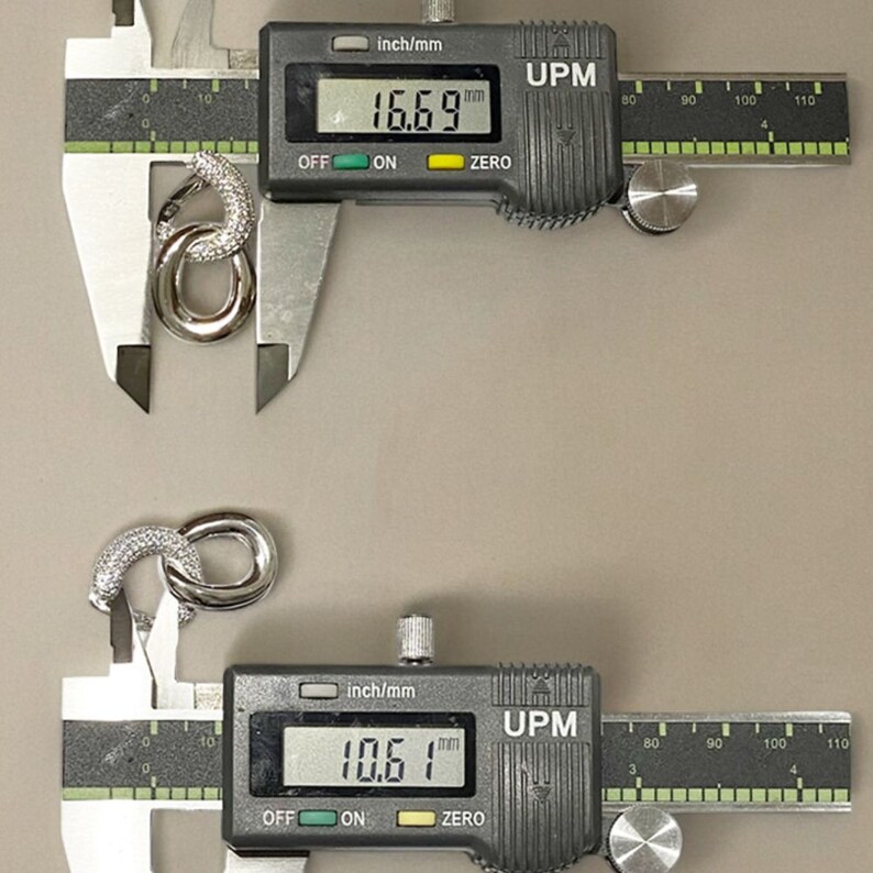 May include: Two silver metal rings with a textured surface, measured with a digital caliper. The top ring measures 16.69 mm and the bottom ring measures 10.61 mm.