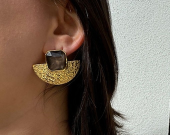 May include: Gold tone earrings with a semi-circular design and a dark gray square gemstone in the center.