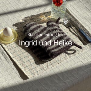 Könnte beinhalten: Ein Stillleben mit einem gestreiften Ofenhandschuh, einem Glas Wasser mit einer roten Blume und einem Ei in einem gelben Eierbecher. Der Text "Strickanleitung für Ingrid und Heike" ist auf dem Handschuh zu sehen.