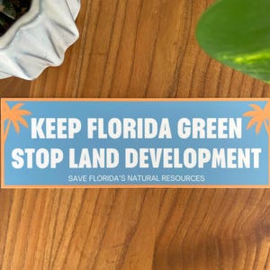 May include: A blue and orange sticker with the text "Keep Florida Green Stop Land Development" and the text "Save Florida's Natural Resources" in smaller font.