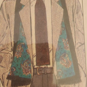 May include: A man wearing a white shirt with a brown tie and a gray jacket with a black and teal paisley scarf. The jacket has a herringbone pattern. The man is wearing brown pants and a brown belt.