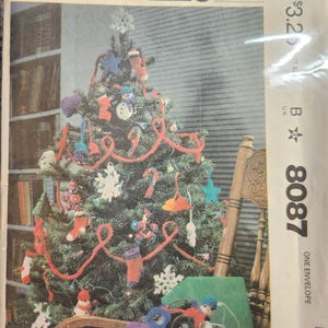 May include: A McCall's sewing pattern envelope featuring a decorated Christmas tree with handmade ornaments and red garland. The envelope includes the text "McCall's" and the pattern number "8087". The designer's signature "Jana Johnson" is also visible.