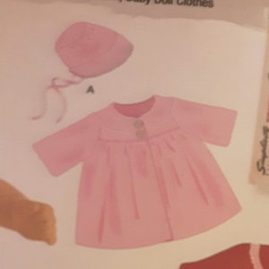 May include: A pink baby doll coat with a button closure and a matching pink hat. The coat has a gathered skirt and short sleeves.