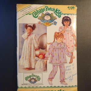 May include: A vintage sewing pattern for Cabbage Patch Kids outfits. The pattern features illustrations of children in pajamas and includes the text "FREE PATTERN" and "BONUS! Iron-on Transfers Included."