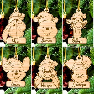 Könnte beinhalten: Sechs hölzerne Weihnachtsbaumschmuckstücke mit Zeichentrickfiguren aus Disneys Winnie Puuh. Jeder Schmuck ist mit einem Namen personalisiert: Noah, James, Oliver, Lucas, Harper und Joseph.