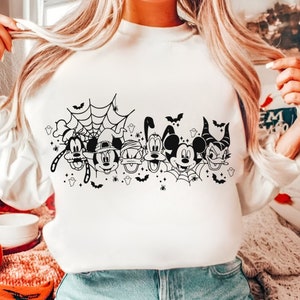 May include: White sweatshirt with a black and white graphic of Mickey Mouse and his friends dressed in Halloween costumes. The graphic includes a spider web, bats, and ghosts.