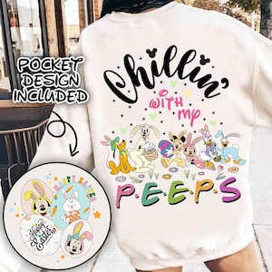 Peut inclure: Sweat-shirt blanc avec un motif de personnages de dessins animés de Disney. Le texte sur le sweat-shirt est "Chillin' with my P.E.E.P.S.". Les personnages sont habillés en costumes de lapin de Pâques et tiennent des œufs de Pâques.