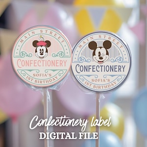Puede incluir: Dos etiquetas redondas de piruletas con un diseño vintage con Mickey Mouse y Minnie Mouse. Las etiquetas son rosa y azul con el texto "Main Street Confectionery Sofia's 1st Birthday".