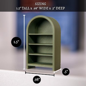 May include: A small, olive green bookshelf with four shelves. The arched top and rectangular base give it a classic look. The dimensions are 1.5 inches tall, .98 inches wide, and .5 inches deep. The word "SIZING" is at the top.