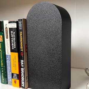 May include: Black bookends with a rounded top, made of a textured material. The bookends are holding up a stack of books, including "Fahrenheit 451" by Ray Bradbury.
