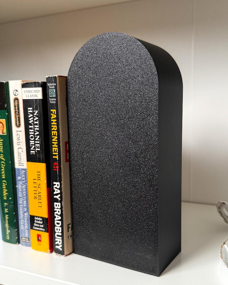 May include: Black bookends with a rounded top, made of a textured material. The bookends are holding up a stack of books, including "Fahrenheit 451" by Ray Bradbury.